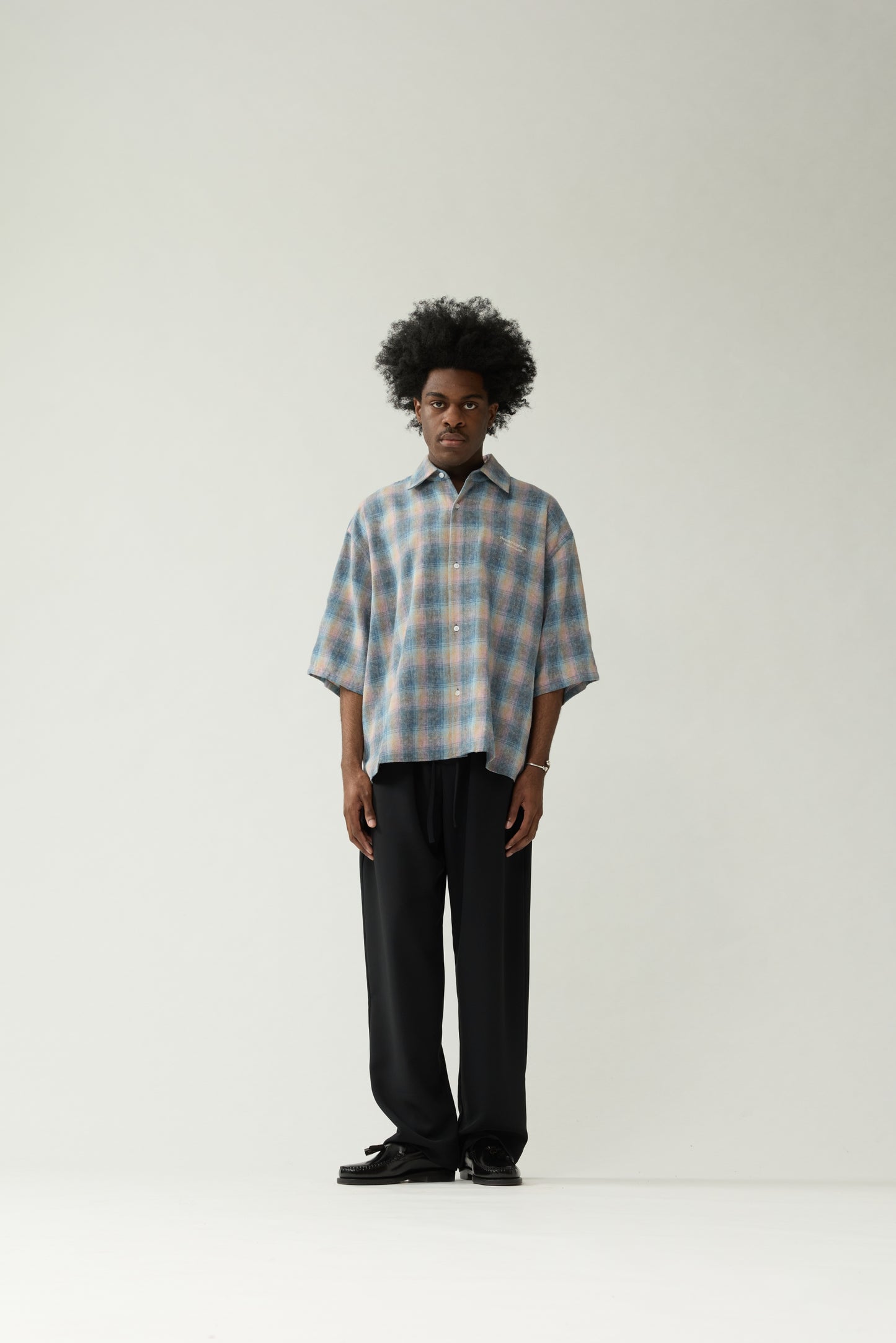 New Amsterdam Surf Association Flanel Short Sleeve Button-Up in Multicolour — male model wearing rainbow check flannel shirt, front view, relaxed unisex fit with dropped shoulders