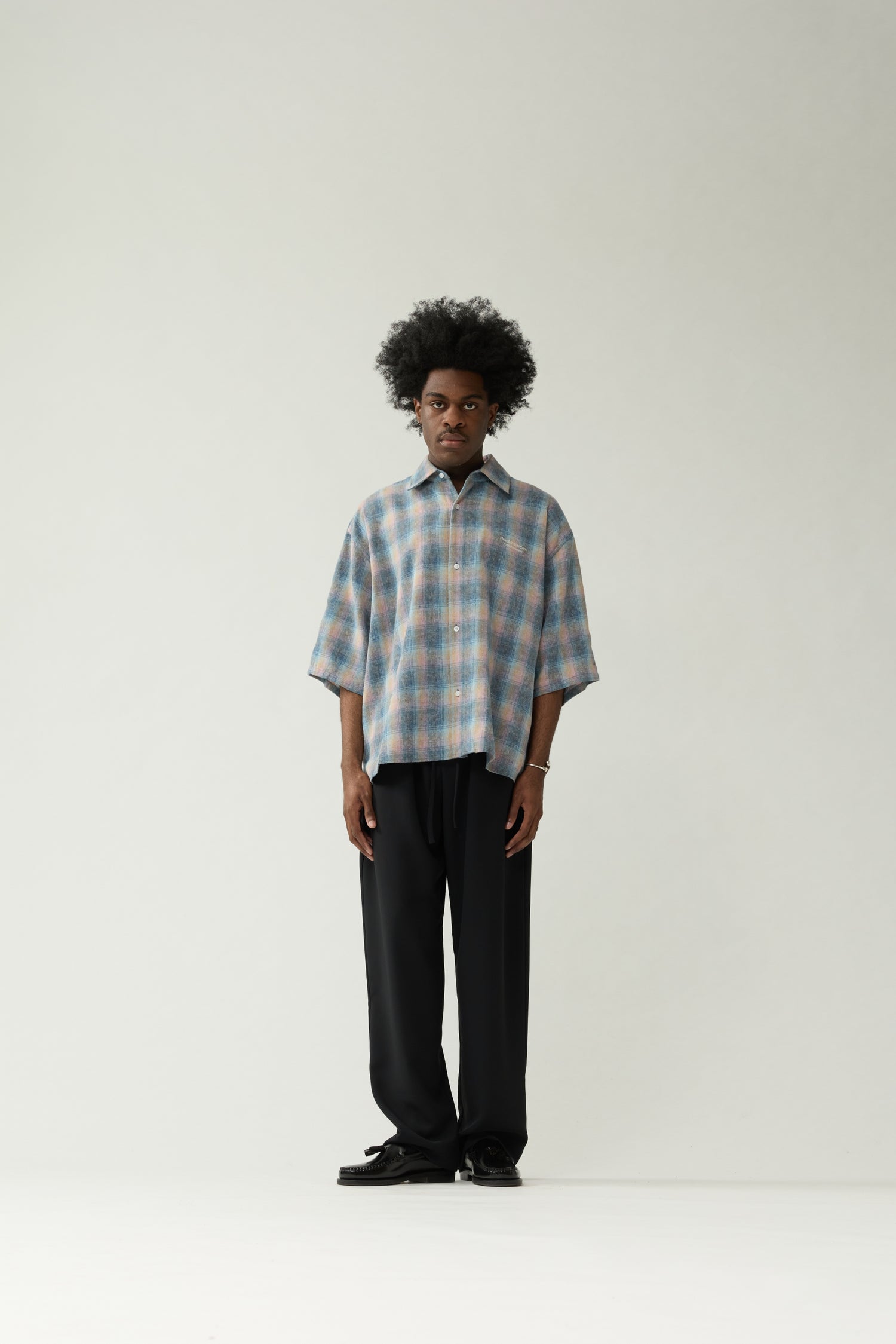 New Amsterdam Surf Association Flanel Short Sleeve Button-Up in Multicolour — male model wearing rainbow check flannel shirt, front view, relaxed unisex fit with dropped shoulders