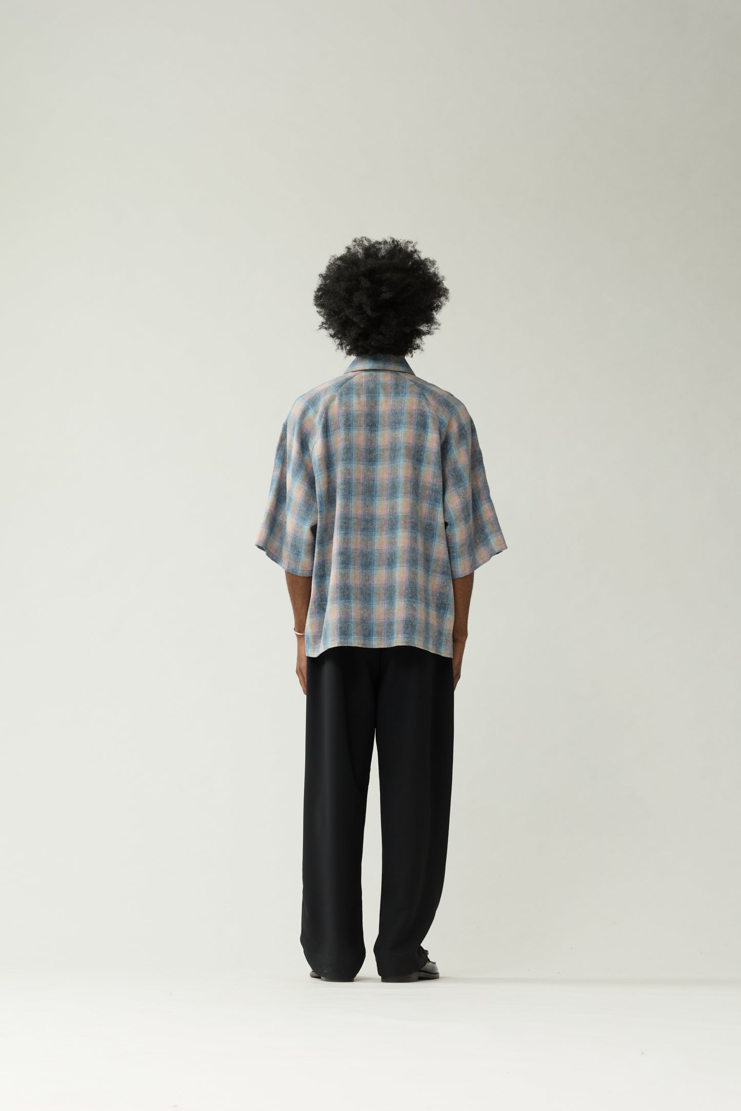 New Amsterdam Surf Association Flanel Short Sleeve Button-Up in Multicolour — male model wearing rainbow check flannel shirt, back view, relaxed unisex fit with dropped shoulders and hip length