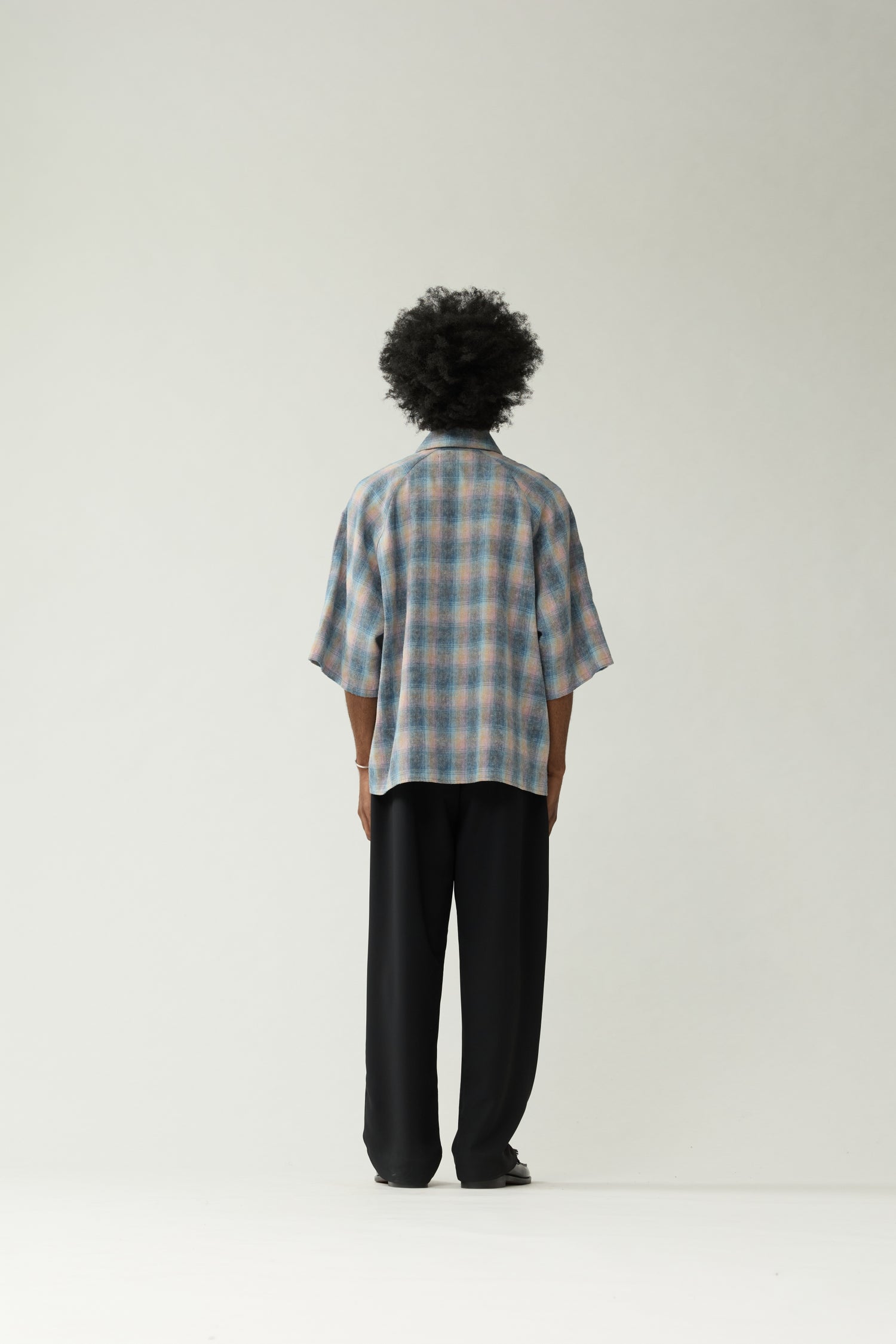 New Amsterdam Surf Association Flanel Short Sleeve Button-Up in Multicolour — male model wearing rainbow check flannel shirt, back view, relaxed unisex fit with dropped shoulders and hip length