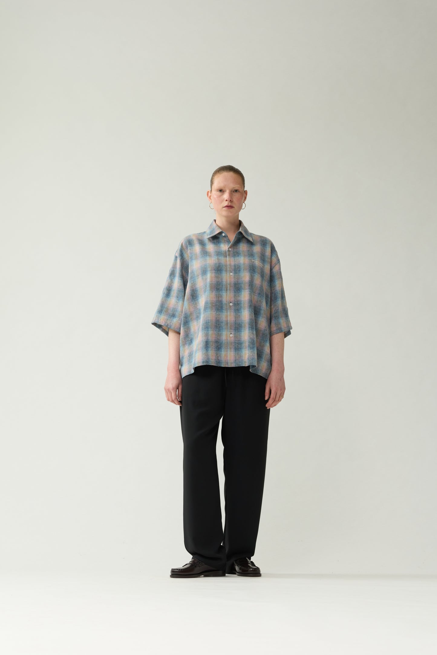 New Amsterdam Surf Association Flanel Short Sleeve Button-Up in Multicolour — female model wearing rainbow check flannel shirt, front view, relaxed unisex fit with dropped shoulders and chest pocket name embroidery