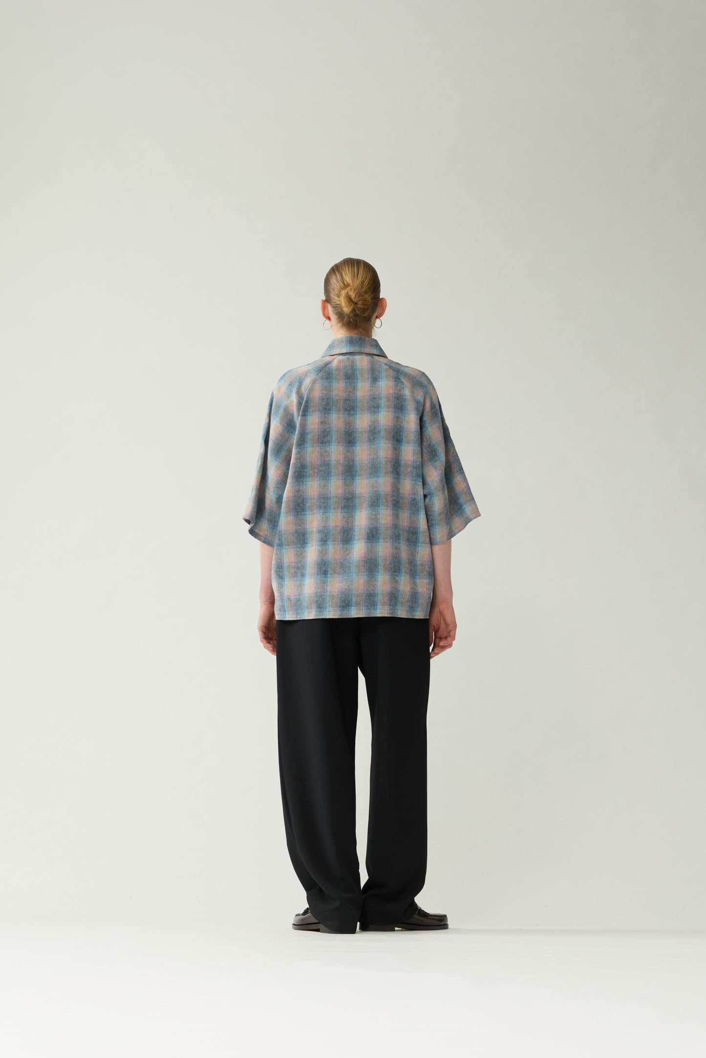 New Amsterdam Surf Association Flanel Short Sleeve Button-Up in Multicolour — female model wearing rainbow check flannel shirt, back view, relaxed unisex fit with dropped shoulders and hip length