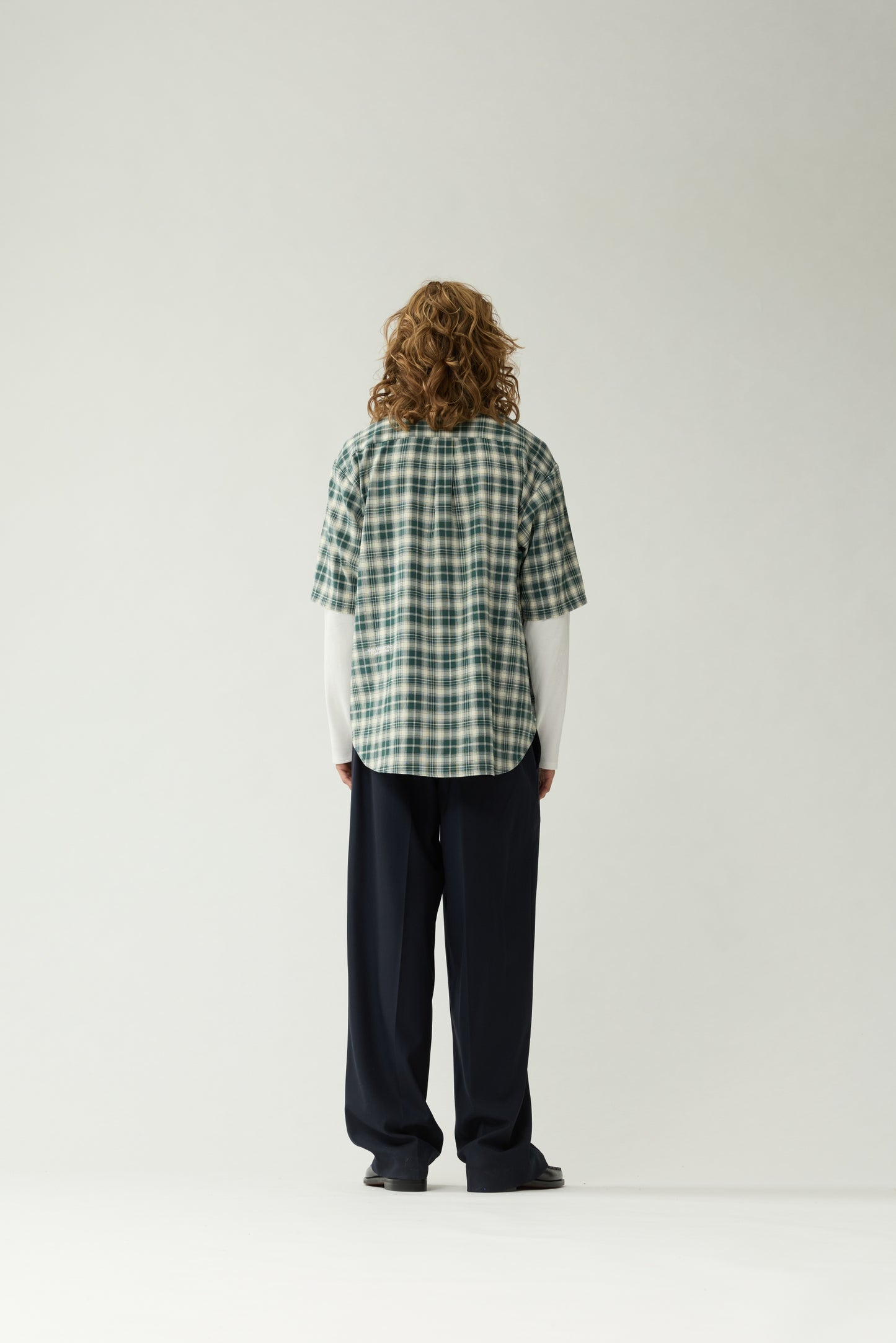 New Amsterdam Surf Association Double Layer Shirt in Green — male model wearing green/white check double layer shirt, back view showing extended hem and white logo embroidery
