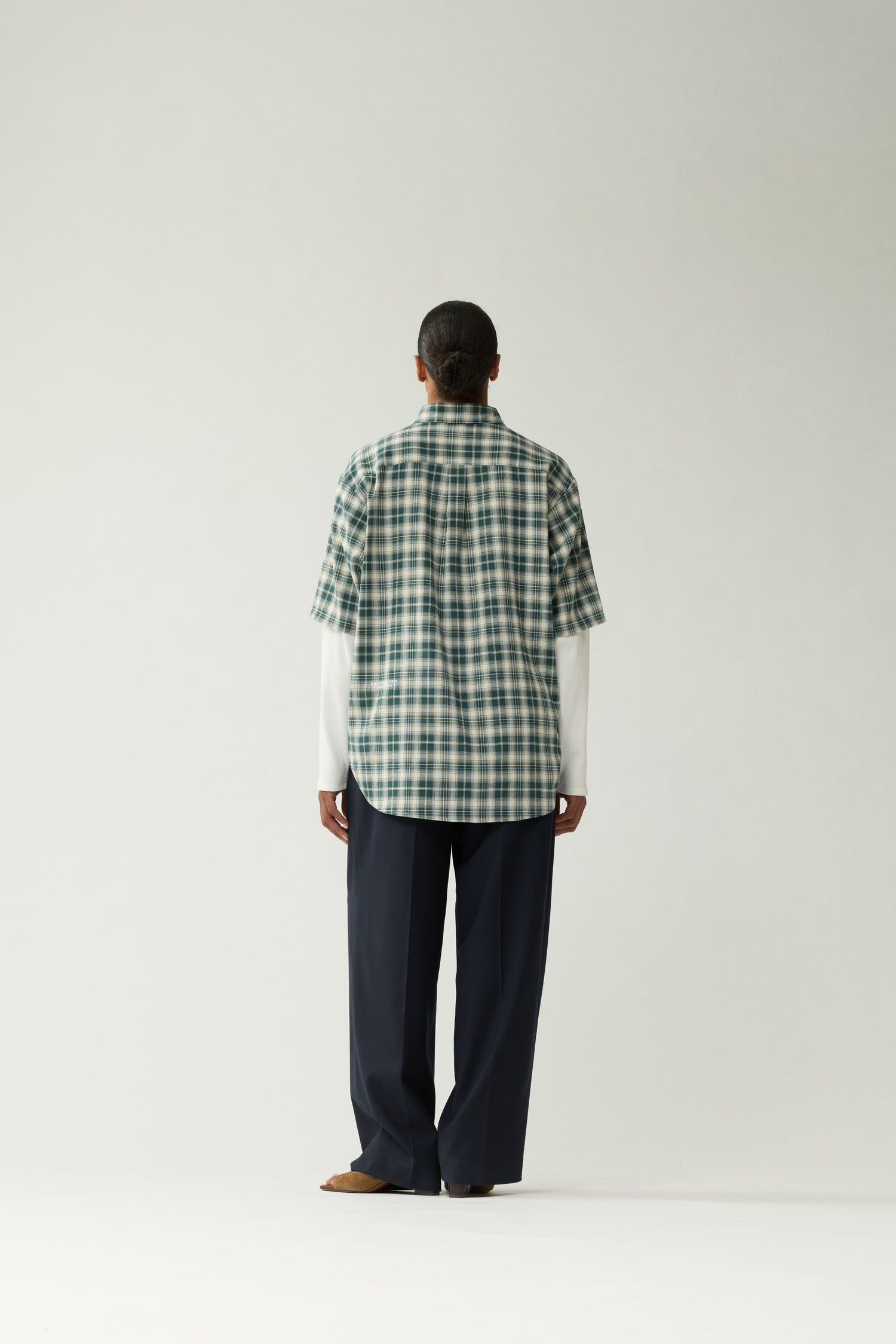New Amsterdam Surf Association Double Layer Shirt in Green — female model wearing green/white check double layer shirt, back view showing extended back hem and white logo embroidery