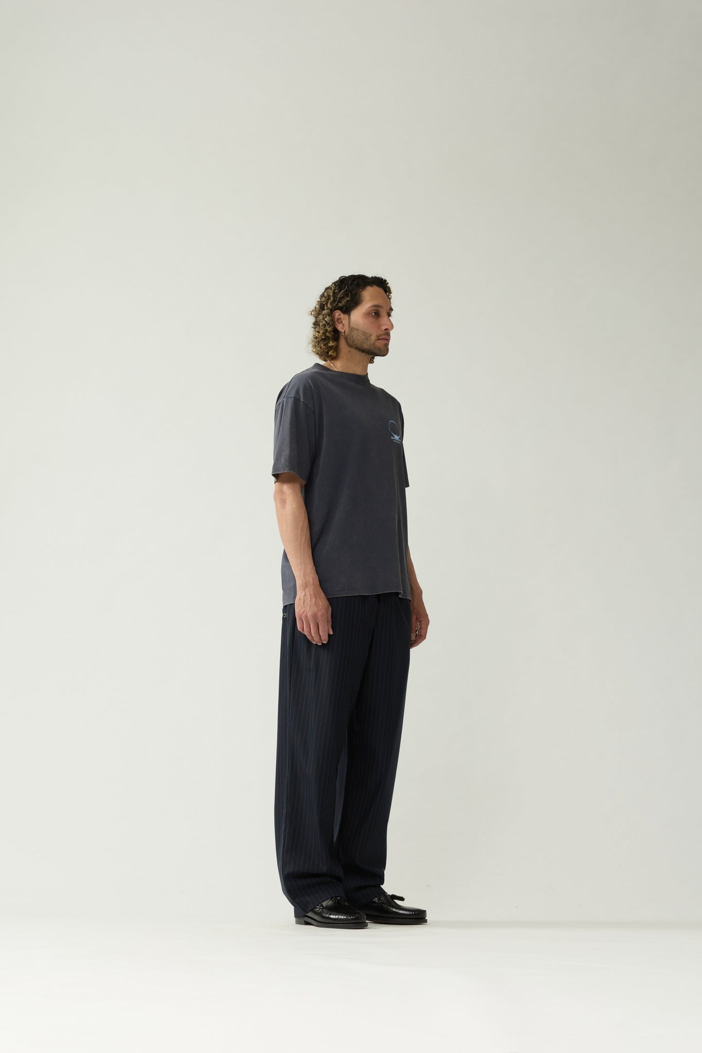 New Amsterdam Surf Association Eclipse Tee in Night — model wearing dark navy crewneck tee, side view, regular unisex fit