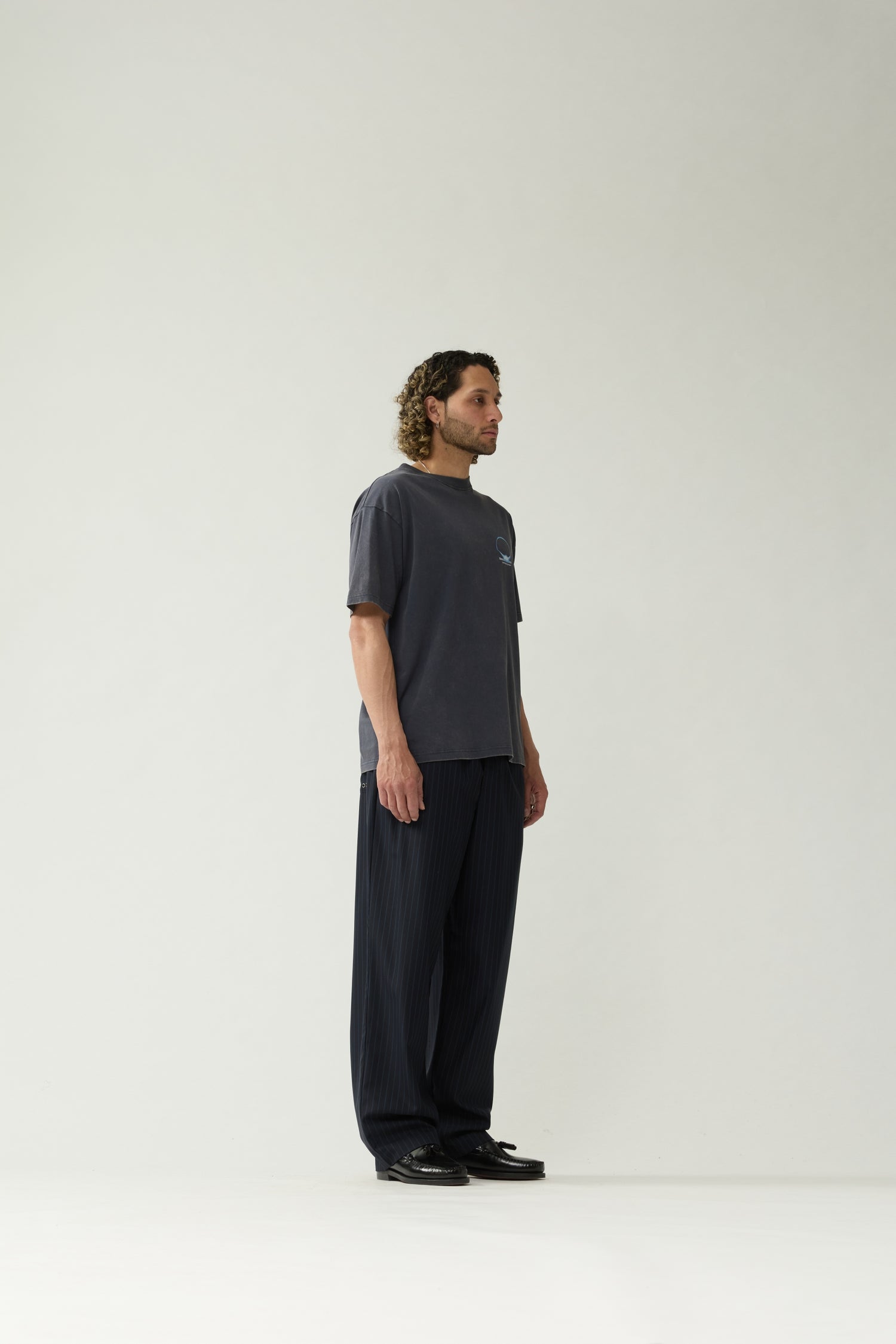 New Amsterdam Surf Association Eclipse Tee in Night — model wearing dark navy crewneck tee, side view, regular unisex fit