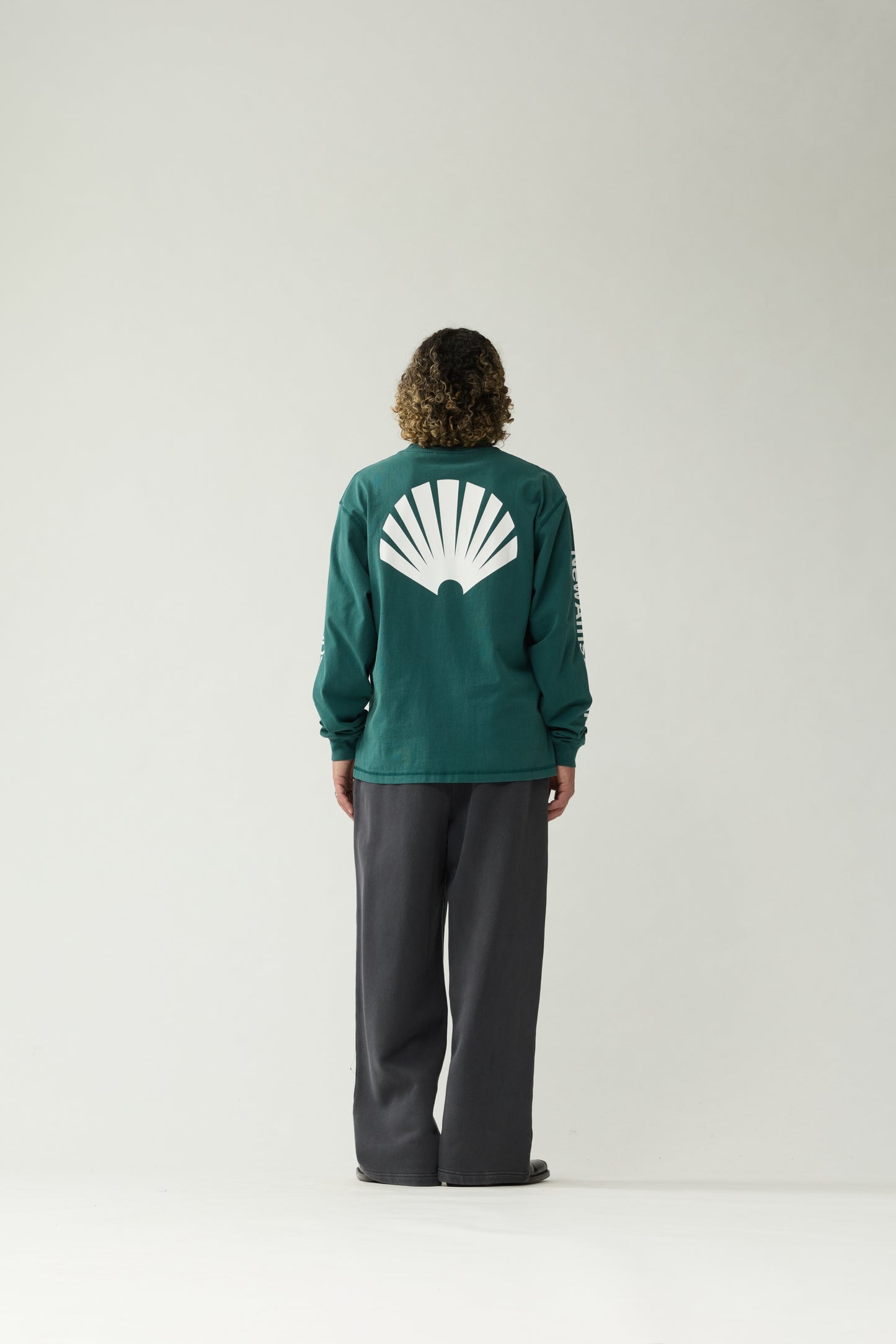 New Amsterdam Surf Association Logo Longsleeve in Bottle Green — male model wearing bottle green longsleeve, back view showing oversized white shell logo screenprint